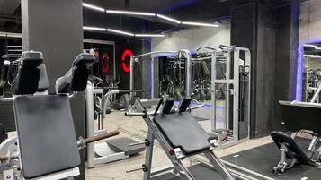 Une salle de sport moderne équipée de divers appareils d’entraînement, notamment des machines à poids et des poids libres.