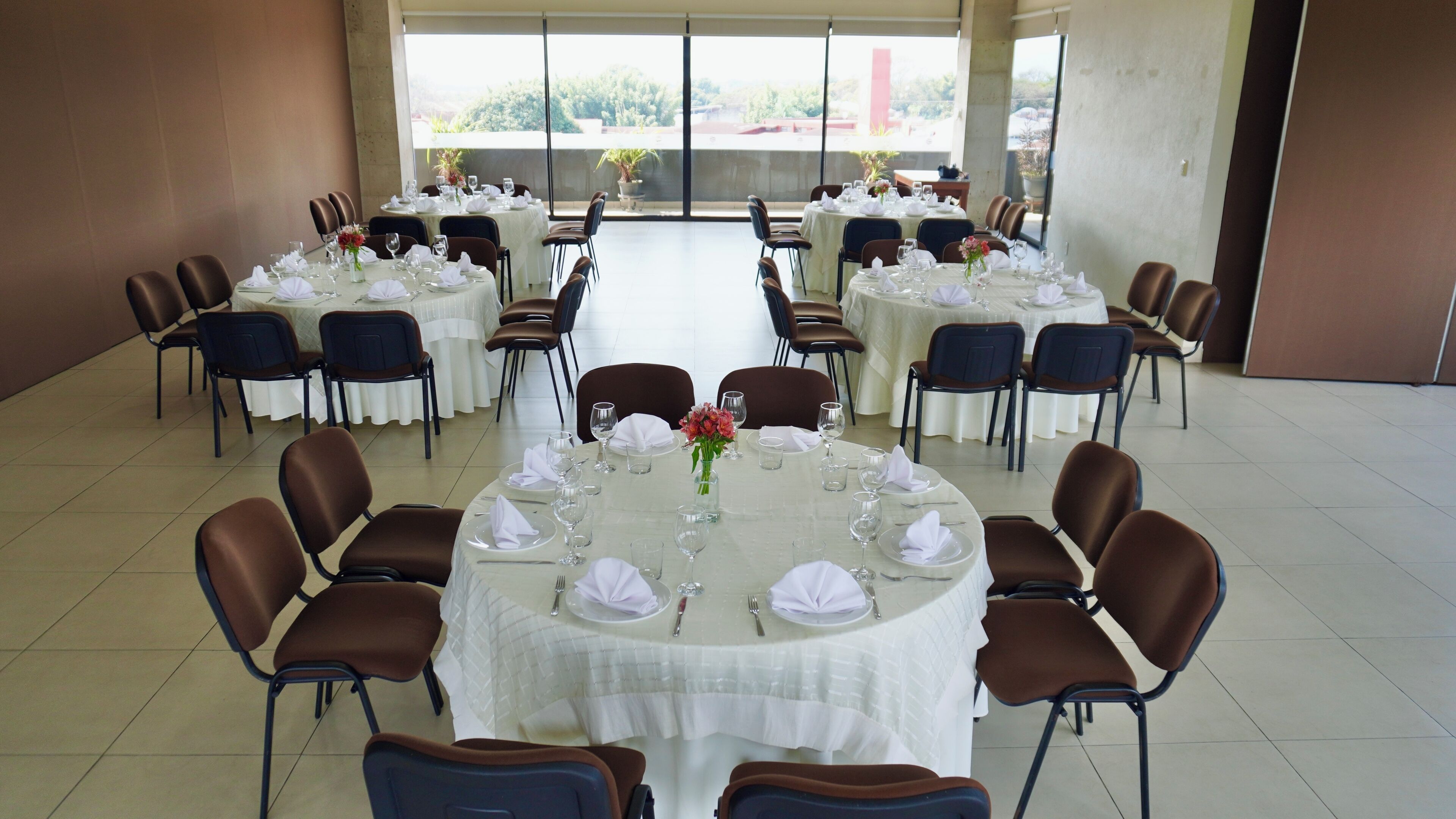 A large banquet hall with round tables set for dining, arranged in rows.