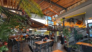 A restaurant with high ceilings, wooden beams, and hanging plants. Tables and chairs are arranged for dining. - Comfort Inn Cordoba (Córdoba)