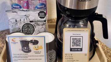 Una cafetera, una botella de agua Nestlé, un folleto de Comfort Inn y una tarjeta de Servicio a la Habitación.