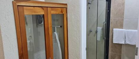 Un baño con un mueble de madera, una cabina de ducha de vidrio y una toalla blanca colgada en la pared.
