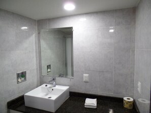 Un baño con un lavamanos blanco, un espejo y un inodoro.