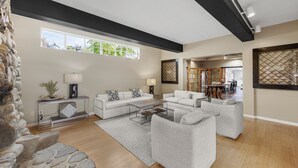 A spacious living room with a stone accent wall, a large window, and a dining area in the background. - Camano Island Inn (Camano Island)