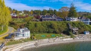 A large, multi-story house with a spacious deck and a small dock extending into the water. - Camano Island Inn (Camano Island)