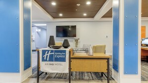 A reception desk with a 'Holiday Inn Express' sign, a flat-screen TV, and a 'Holiday Inn Express' banner.