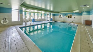 An indoor swimming pool with clear water, tiled walls, and a blue and white color scheme.