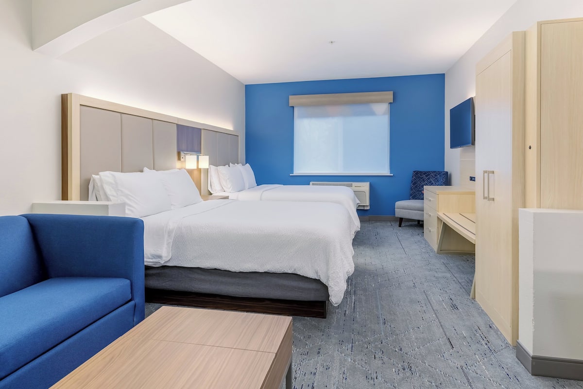 A hotel room with a bed, a blue sofa, a desk, and a wardrobe.