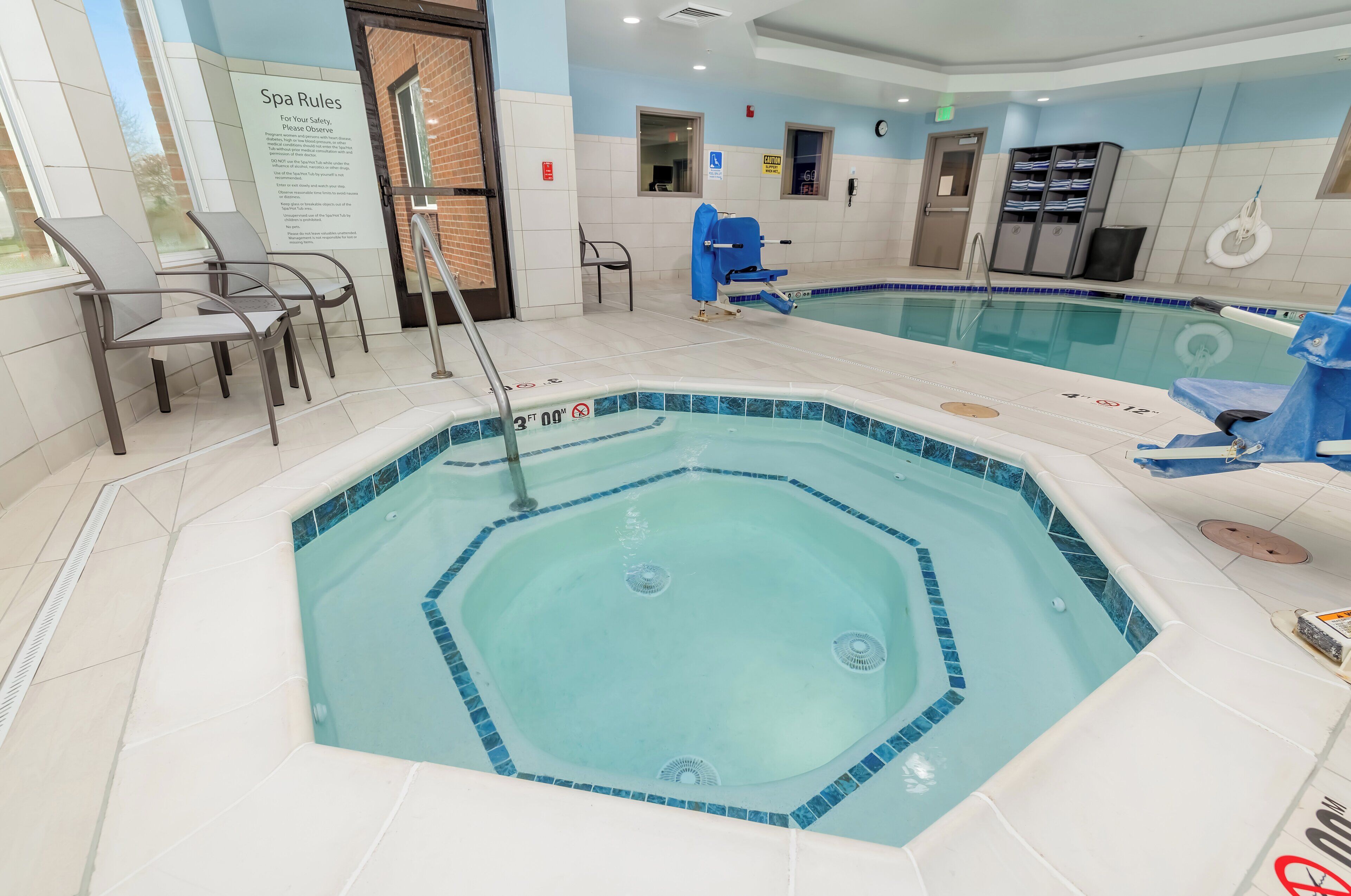 Ein Hotelpoolbereich mit Whirlpool, Liegestühlen und einem Schild mit den Spa-Regeln.