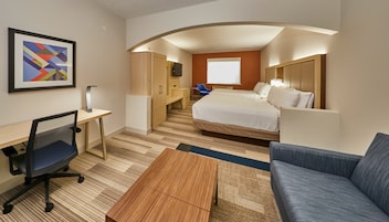 A hotel room with a bed, desk, chair, and a small table.