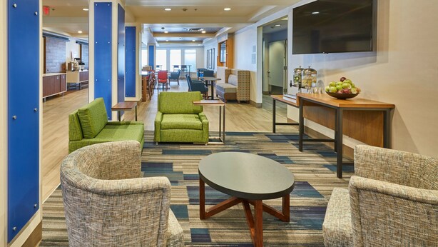 A hotel lobby with seating areas, a television, and a bowl of fruit on a table.