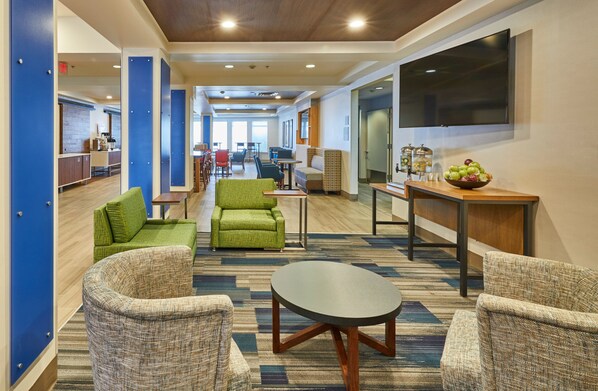A hotel lobby with seating areas, a television, and a bowl of fruit on a table. - Holiday Inn Express Hotel & Suites Medford-Central Point by IHG (Central Point)