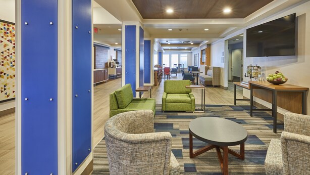 A hotel lobby with blue lockers, green seating, a flat-screen TV, and a coffee station. - Holiday Inn Express Hotel & Suites Medford-Central Point by IHG (Central Point)