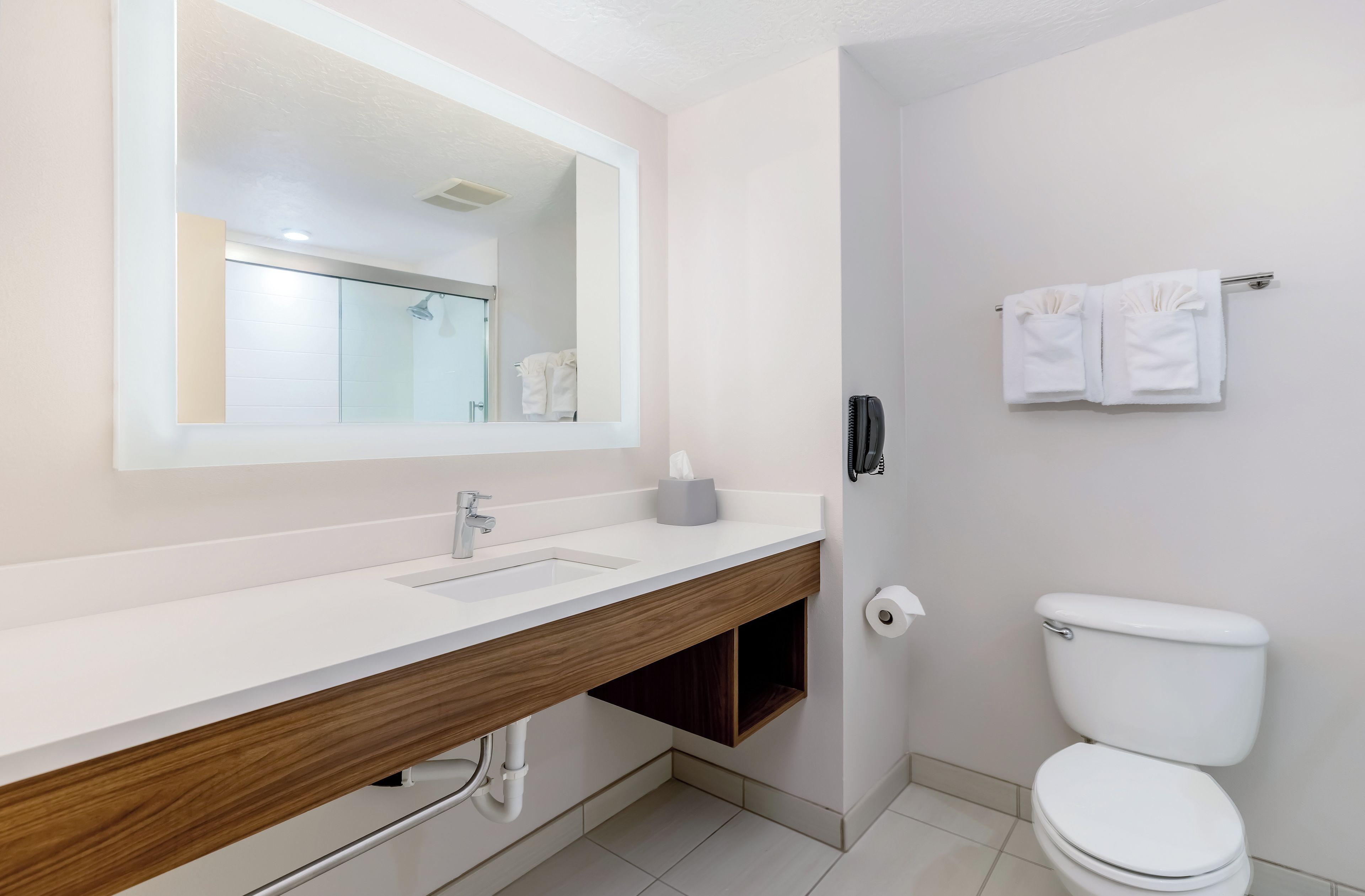 A modern bathroom with a white sink, mirror, and toilet.