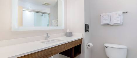 A modern bathroom with a white sink, mirror, and toilet.
