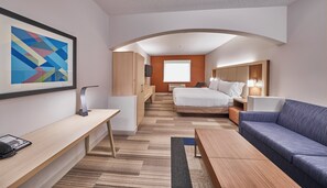 A hotel room with a bed, a desk, a sofa, a TV, and a large abstract painting on the wall. - Holiday Inn Express & Suites Medford-Central Point (Central Point)
