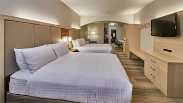 Habitación de hotel con dos camas, un escritorio, una silla, un televisor y un armario.