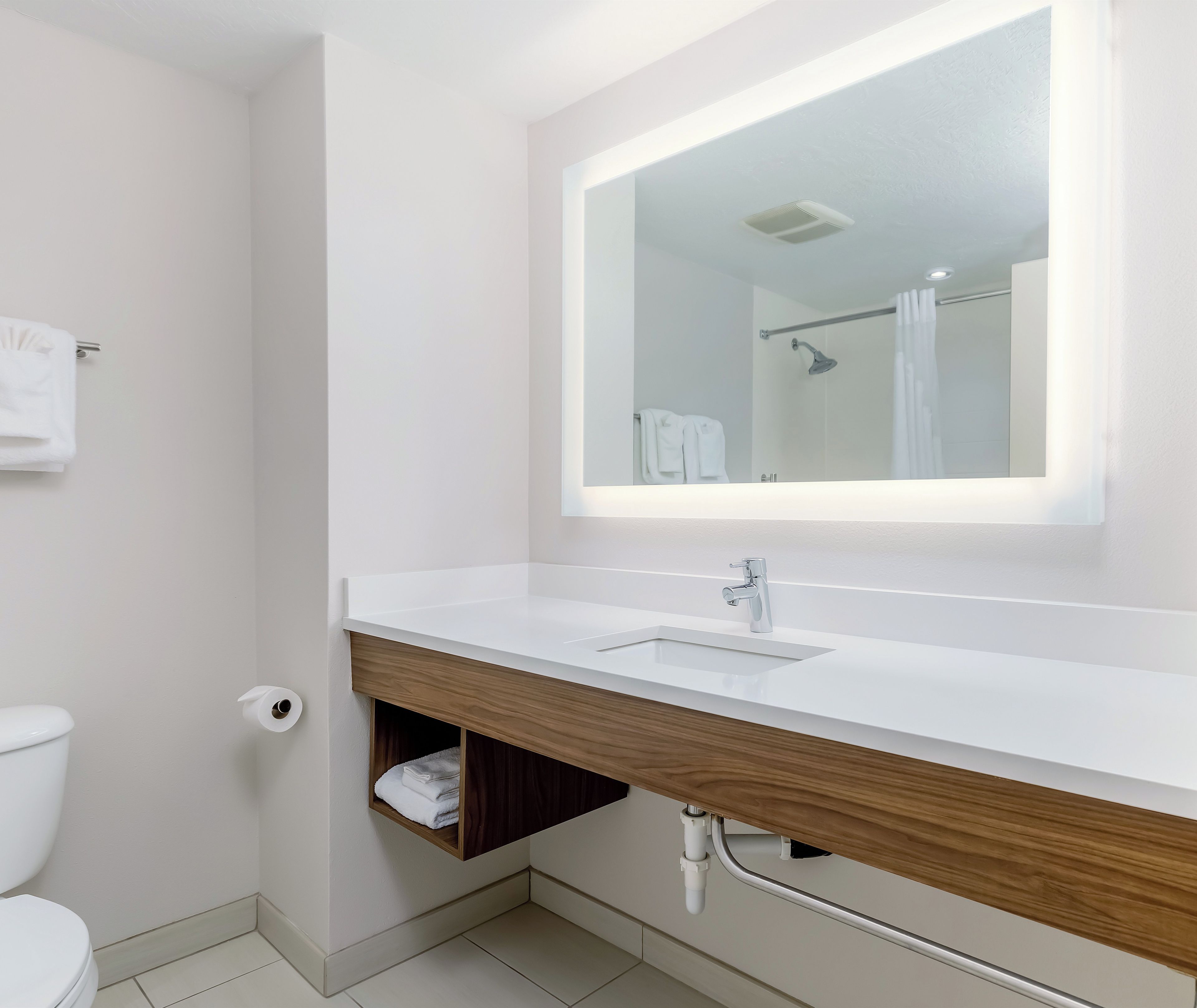 Un baño moderno con un lavamanos blanco, un espejo y una ducha.
