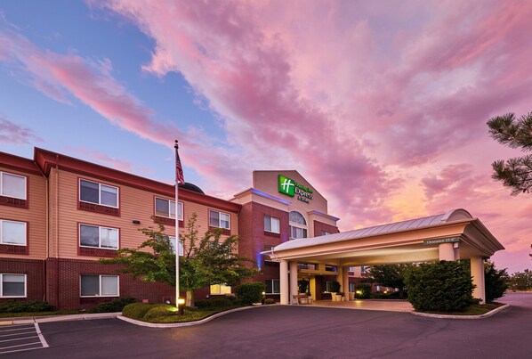 Un hotel con entrada despejada, un asta de banderas y un cartel que indica que es un Holiday Inn Express.