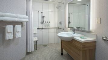 Une salle de bain moderne équipée d’une douche, d’un lavabo, d’un miroir et d’un porte-serviettes.