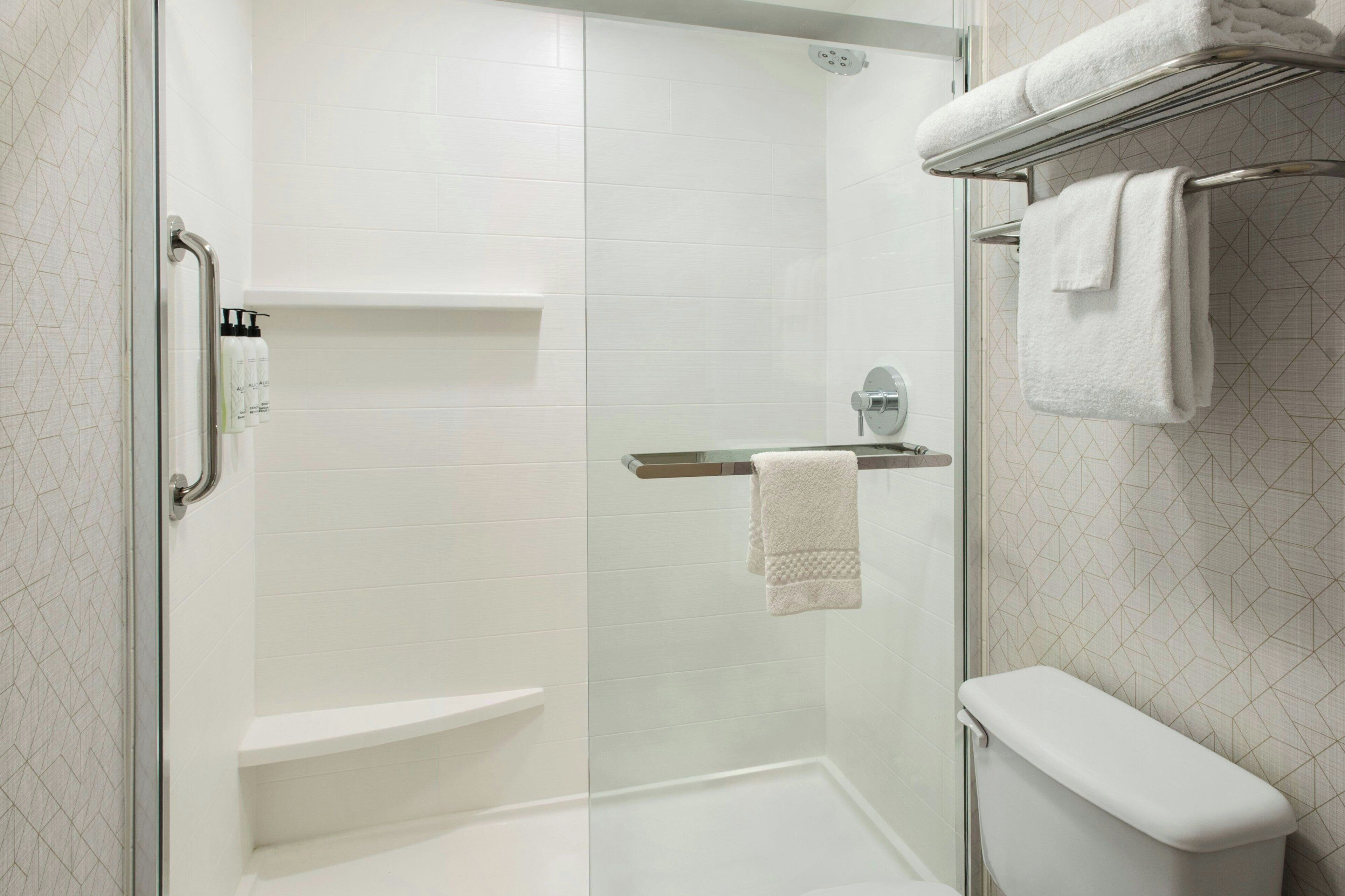 A modern bathroom with a glass-enclosed shower, a white toilet, and a towel rack.