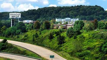 A highway with a sign for Pittsburgh Mills, a large building in the background, and a green road sign indicating Exit 12 A.