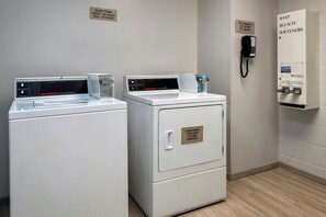 A laundry area with two front-loading washers and a dryer, a phone, and a soap and bleach softener cabinet. - Springhill Suites by Marriott Pittsburgh Mills (Tarentum)