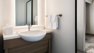 Un baño moderno con un lavamanos grande de color blanco, tocador de madera, un espejo y un perchero para toallas.