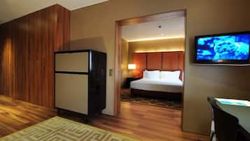 A hotel room with a bed, a television, a desk, and a refrigerator.
