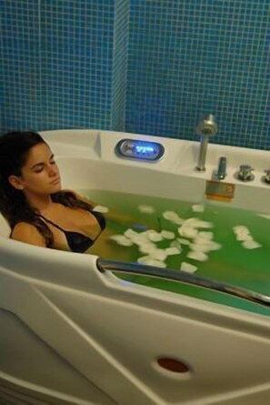 A bathtub with a digital display, a handheld showerhead, and a green bath mat. - Hotel de Guimarães (Guimarães)