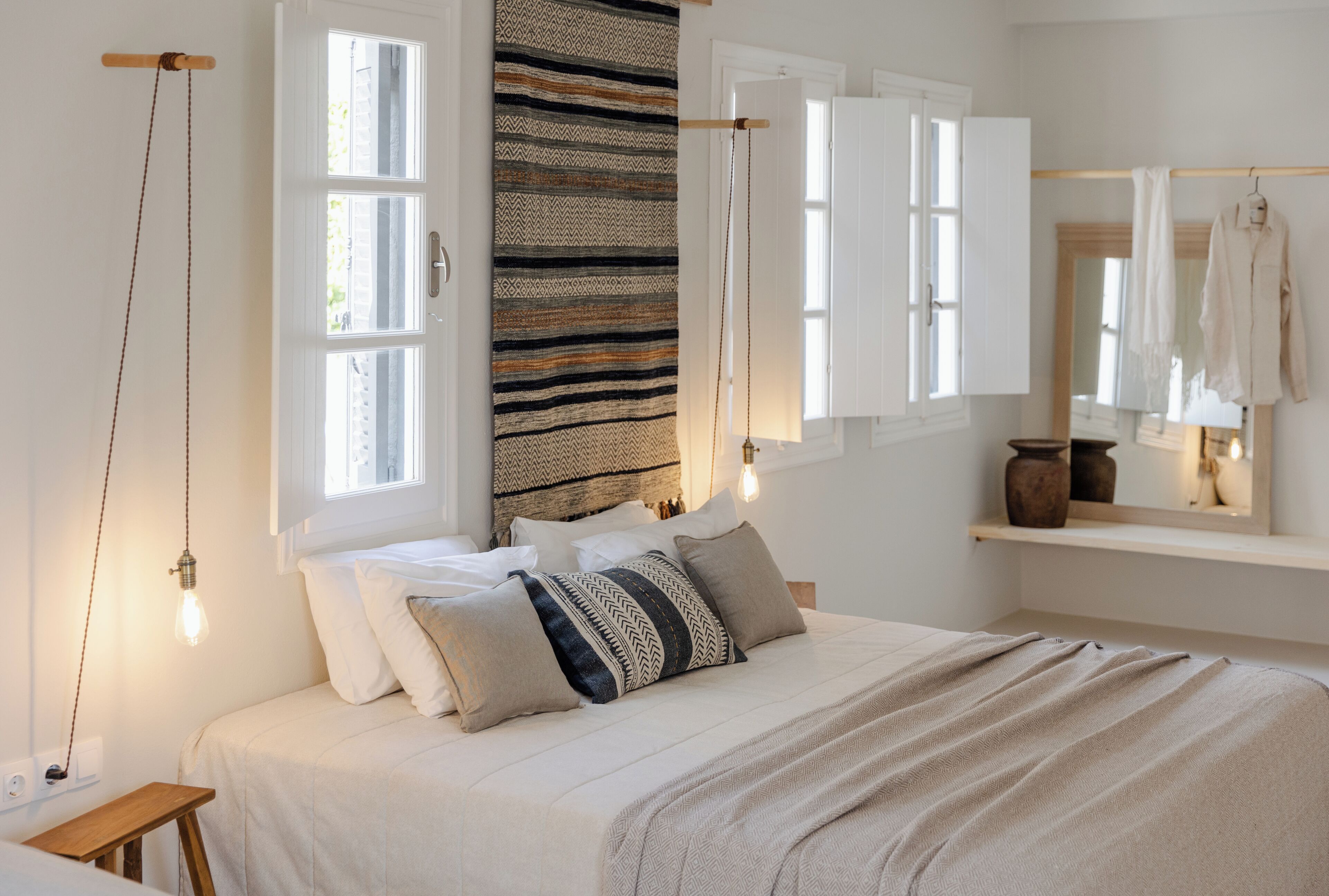 Un dormitorio con una cama, una ventana, una lámpara colgante y un espejo.