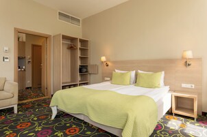 Una camera d'albergo con un letto, una sedia, un armadio e un comodino.