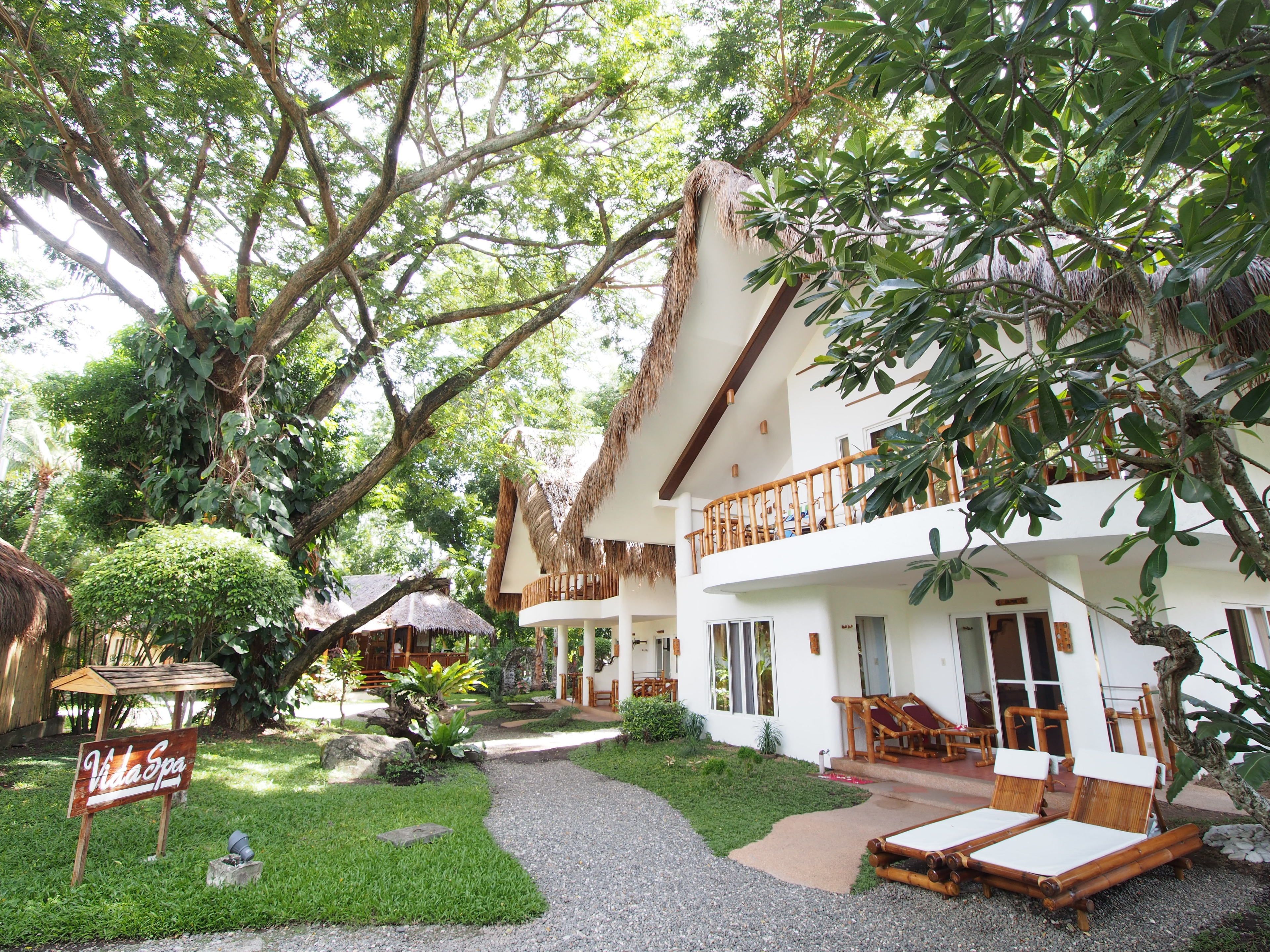 A resort with a thatched-roof building, a covered outdoor seating area, and a sign reading "Vida Spa".