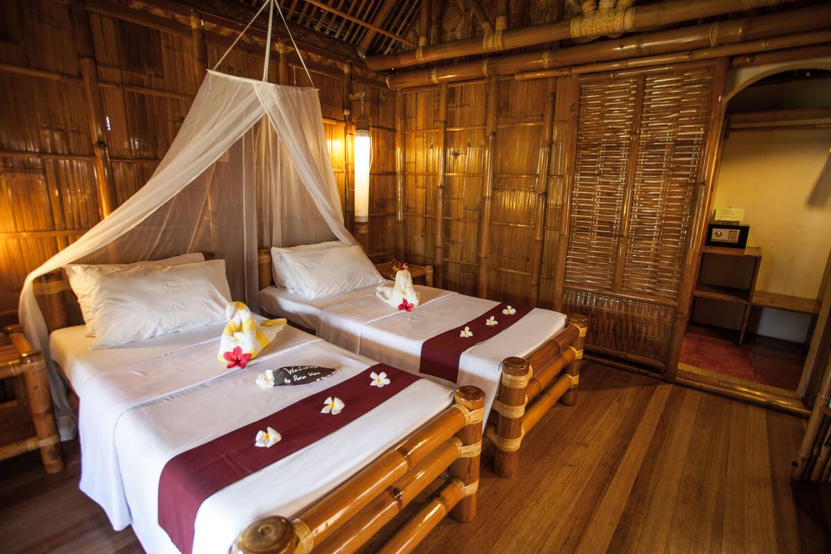 Una habitación con dos camas, cada una con dosel, cabeceros de madera y colcha roja.