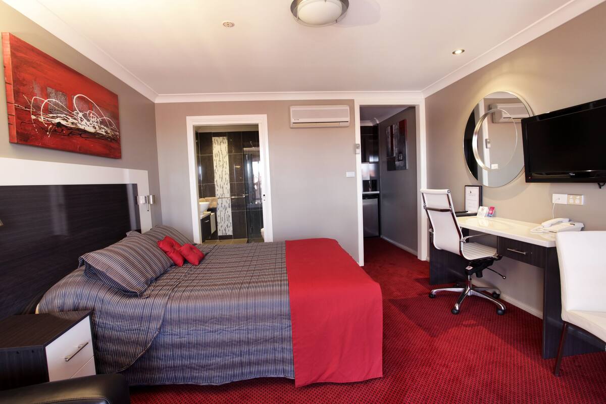 Une chambre d’hôtel équipée d’un lit, d’un bureau, d’une chaise et d’un téléviseur.