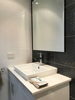 Un baño moderno con un lavabo blanco, un espejo y un salpicadero de azulejos negros.
