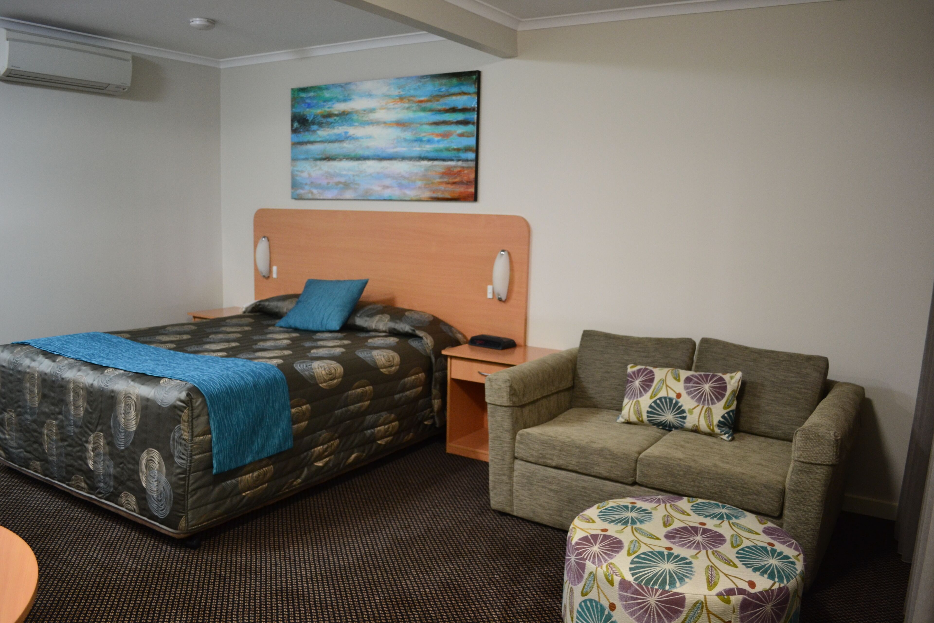 Ein Hotelzimmer mit einem Bett, einer Couch, einem kleinen Tisch und einem Bild an der Wand.