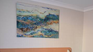 Habitación de hotel con dos camas, cabecera de madera, mesita de noche con toallas y un cuadro en la pared.