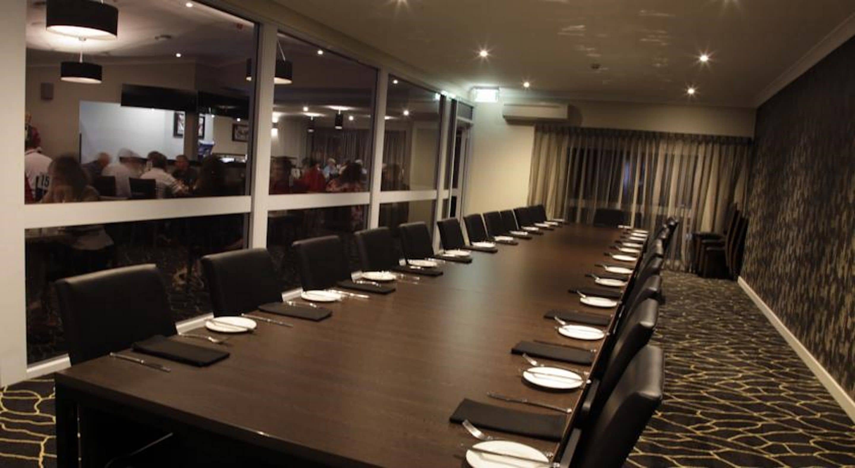 A conference room with a long table, black chairs, and white plates.