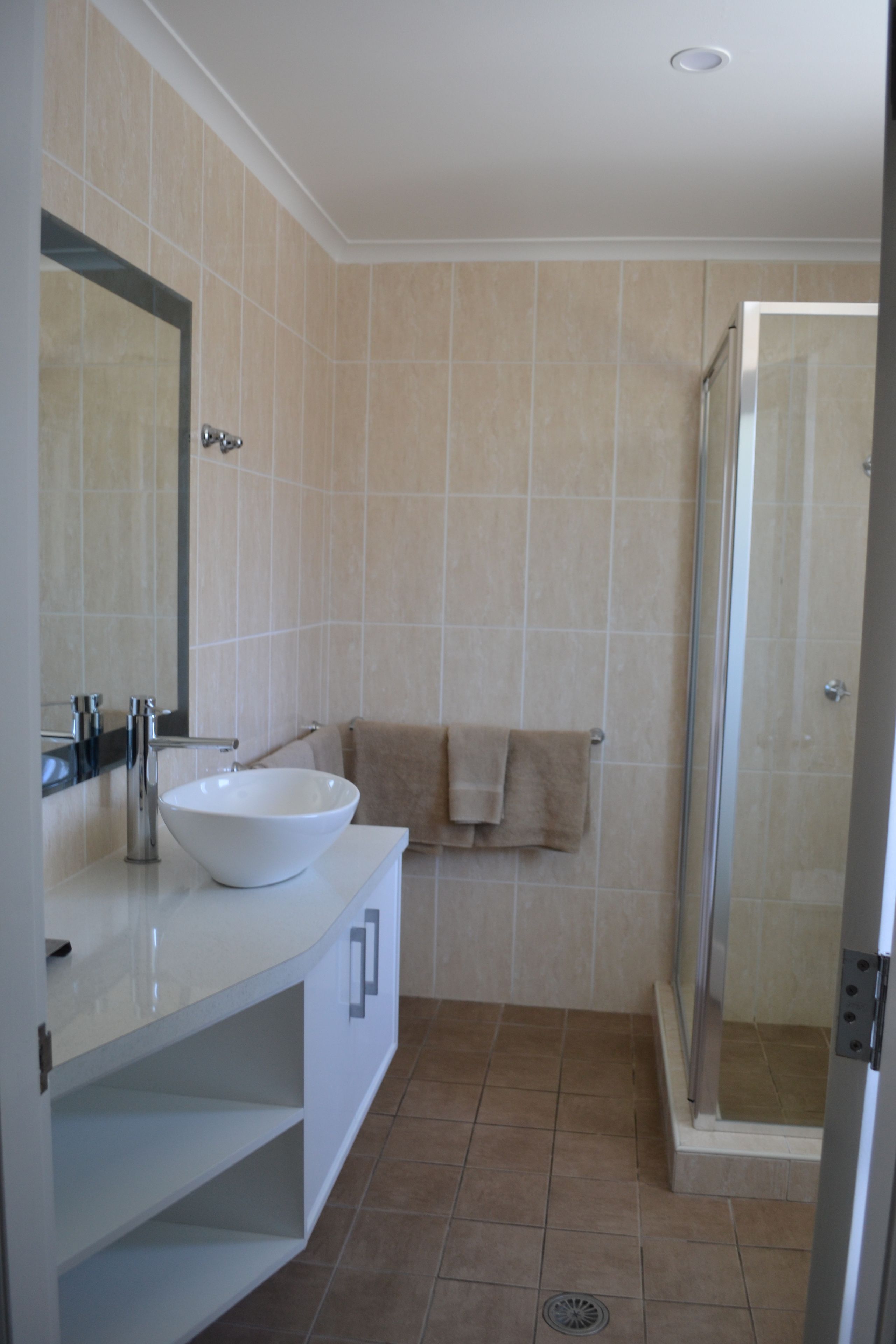 A bathroom with a white sink, a mirror, and a shower area.