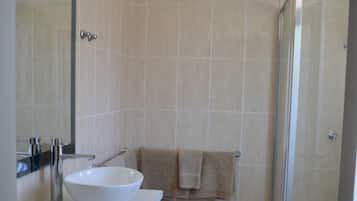 A bathroom with a white sink, a mirror, and a shower area.