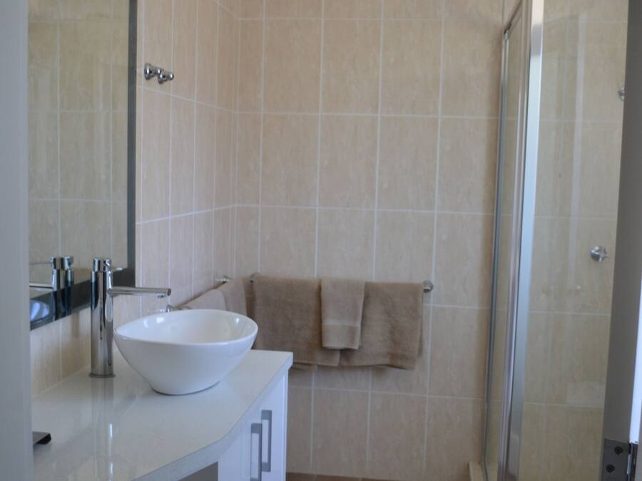 A bathroom with a white sink, a mirror, and a shower area.