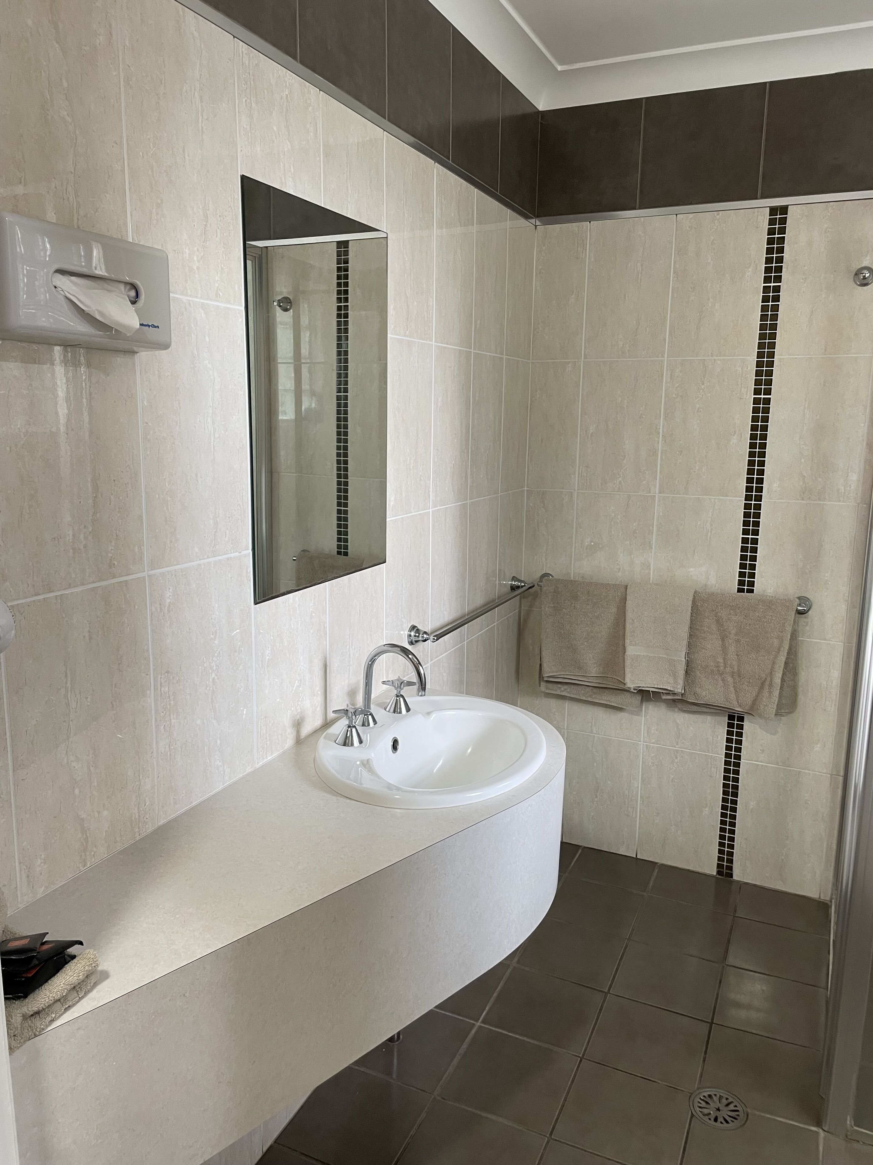 A bathroom with a white sink, a mirror, and a towel rack.