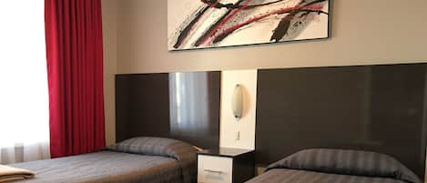A hotel room with two beds, a nightstand, a mirror, and a painting on the wall.