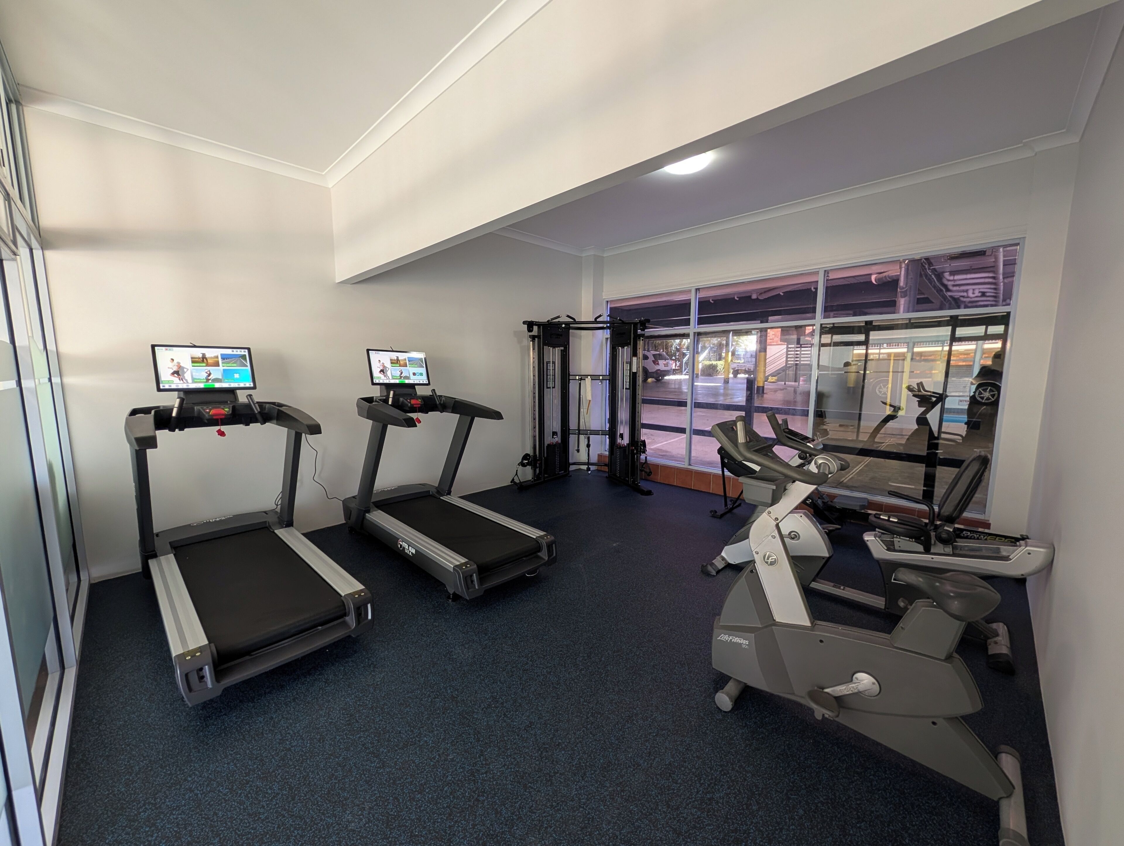 Ein Fitnessraum mit Laufbändern, einem Kraftgerät und einem Rudergerät.