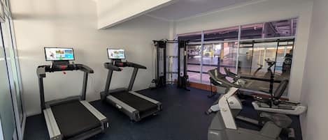 Ein Fitnessraum mit Laufbändern, einem Kraftgerät und einem Rudergerät.