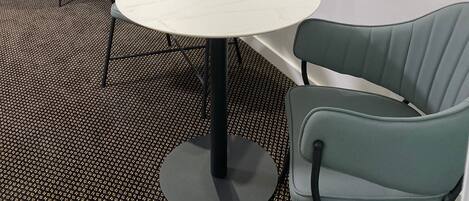 Una habitación de hotel con una mesa redonda, dos sillas, un escritorio, un espejo y un televisor montado en la pared.