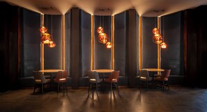 A modern interior with round tables and chairs, vertical light fixtures, and a wooden floor.