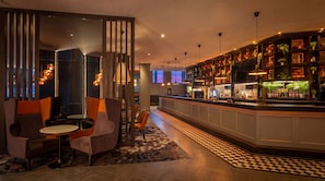 A bar area with a checkered floor, bar counter, and seating with round tables and chairs. - Clayton Hotel Leeds (Leeds)