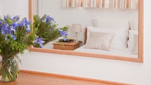 A bedroom with a wooden headboard, a bedside table with a lamp, and a mirror reflecting the room. - At Winkfield House (Cape Town)