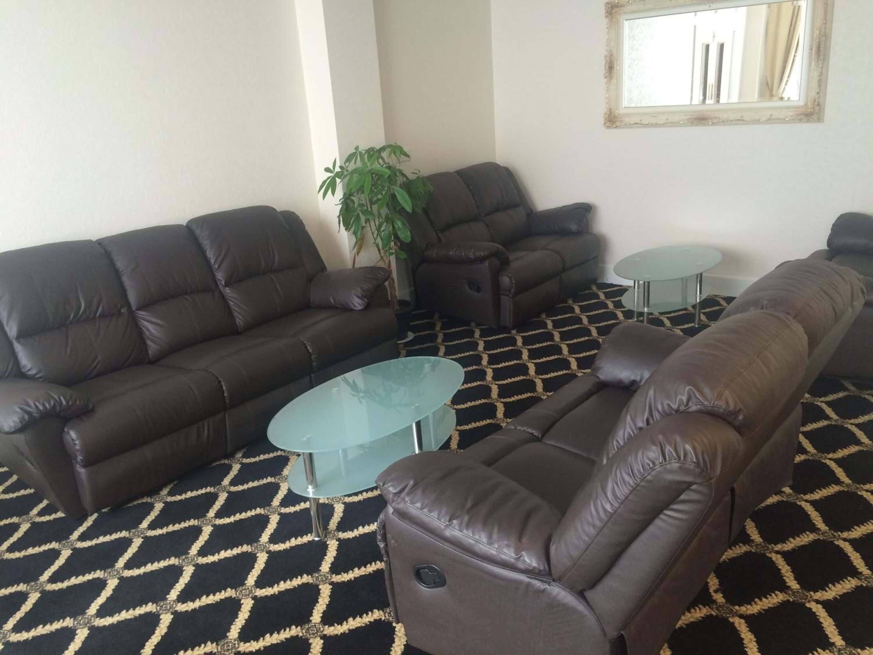 A living room with two sofas, a glass coffee table, and a potted plant.